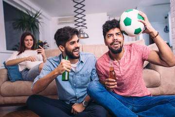 Happy friends or football fans watching soccer on tv and celebrating victory at home.Friendship, sports and entertainment concept.