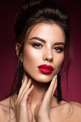 Gorgeous Young Brunette Woman face portrait. Beauty Model Girl with bright eyebrows, perfect make-up, red lips, touching her face. Sexy lady makeup for party.