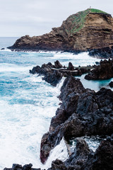 Rocky shore and blue ocean during cloudy day in Porto Moniz, Madeira, Portugal