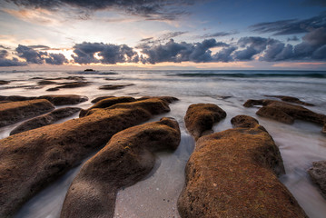 Serinity view of sunset seascape with natural coastal rocks on the beach.