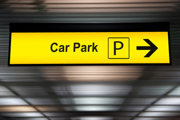 yellow car park sign with arrow pointing to car parking zone at airport terminal