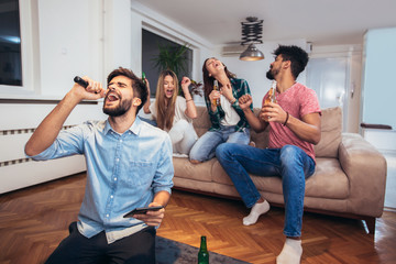 Group of friends playing karaoke at home. Concept about friendship, home entertainment and people