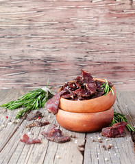 jerked meat, cow, deer, wild beast or biltong in wooden bowls on a rustic table, selective focus