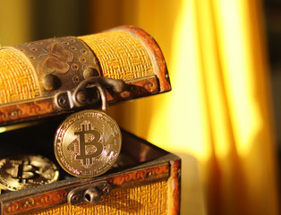 The gold coin bitcoin looks out of the chest with bitcoins in the rays of sunlight. Warm yellow...