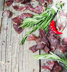 jerked meat, cow, deer, wild beast or biltong in wooden bowls on a rustic table, selective focus