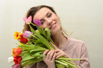Naklejka premium Young charming girl with a bouquet of flowers - multi-colored tulips