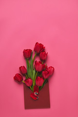 top view of red tulips in envelope on pink, mothers day concept