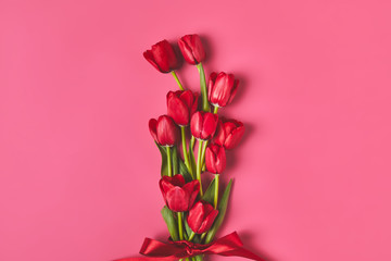 top view of red tulips tied with ribbon on pink, mothers day concept