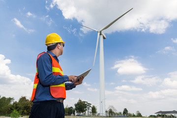 Fototapeta na wymiar Electric Engineer use Tablet Device with Wind turbine power Generator Tower