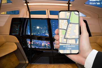 Hand with phone on a background of interior od autonomous taxi. Control of self driving shuttle by mobile app. Concept.