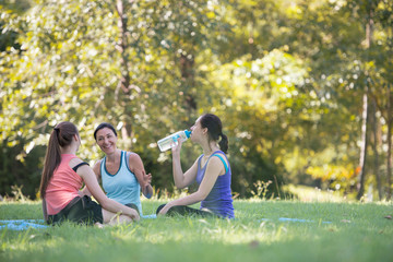 Families with young Russian mother and daughter are talk about exercise and Drink Water. After practice yoga at the park finished. Health and Fitness concept