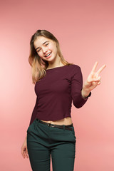 Woman smiling with perfect smile and white teeth on the pink studio background and looking at camera