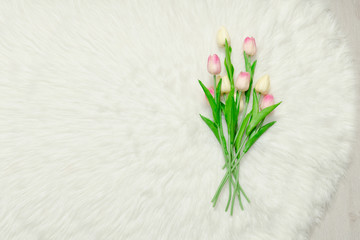 Bouquet of tulips on white fur. Space for text