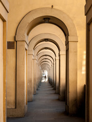 Passageway in Florence with round arches and person at the end