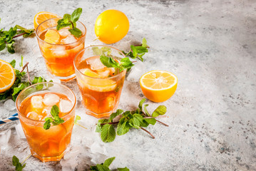 Cold summer drink. iced tea with lemon and mint, on grey stone background.  Copy space