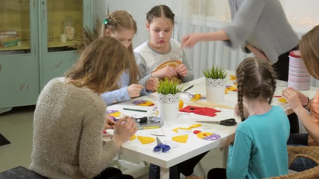 Girls at the lesson with the teacher sew a soft toy with their own hands