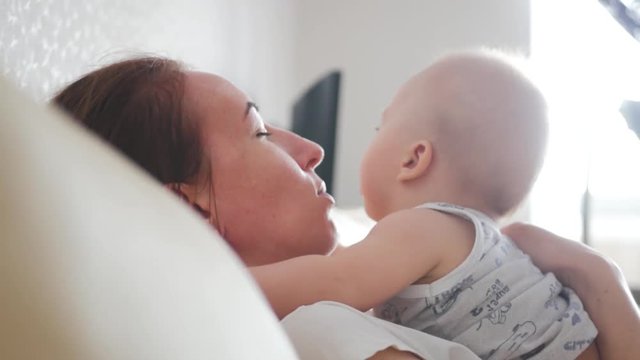 Young mother kissing sweet baby boy. Motherhood, family and parenthood concept - happy smiling young mother with little baby at home.