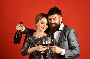 Woman in sparkling dress and man holding bottle of wine
