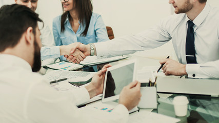 handshake business partners after discussing the terms of a contract in the workplace in the office.