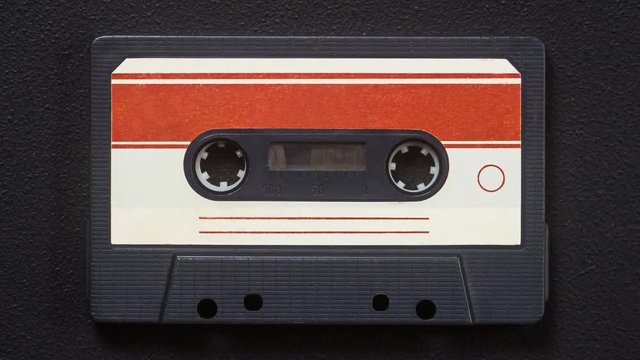 Old tape cassette spin on a black background. 4k. Stop Motion.