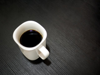 Hot black coffee in white cup on table