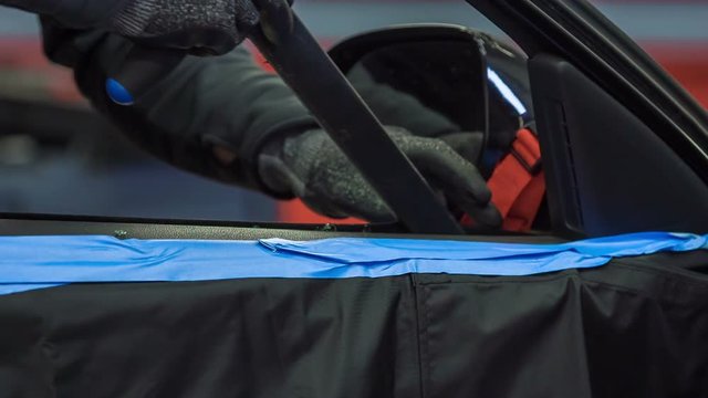 A young mechanic is working on fixing a car window because the glass window has been broken.