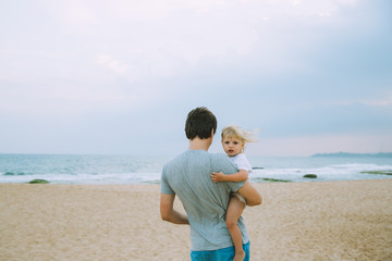 Father carries his daugher on the beach