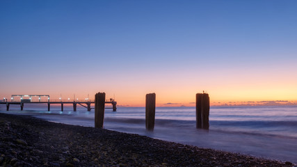A pier on a rocky beach, sunset background