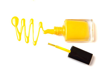 Nail polish of yellow color spilled on a white isolated background