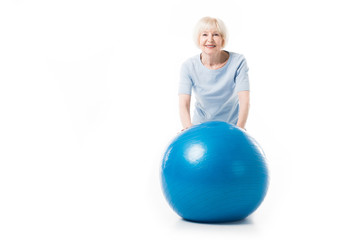 Portrait of smiling senior sportswoman with fitness ball isolated on white