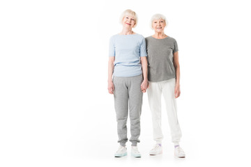 Two smiling senior sportswomen standing isolated on white