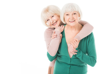 Two senior stylish women hugging isolated on white