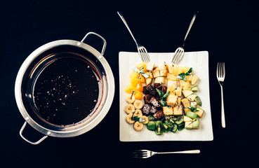 chocolate fondue with fruits on black table