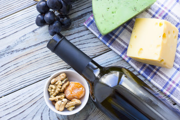 Snacks with wine - bottle of wine, various types of cheeses, figs, nuts, honey, grapes on a blue wooden background