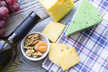 Snacks with wine - bottle of wine, various types of cheeses, figs, nuts, honey, grapes on a blue wooden background