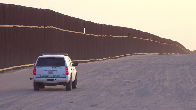 Border patrol vehicle moves near the border wall at the US Mexico border at Imperial sand dunes, California.