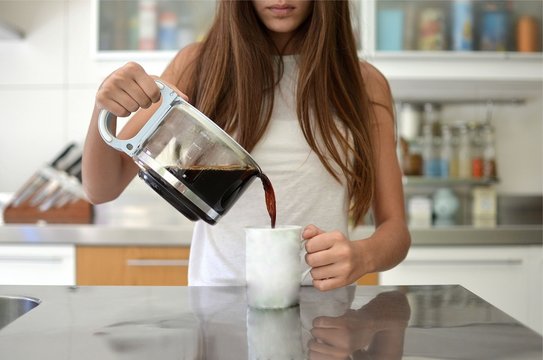 Girl Pouring A Cup Of Coffee In The Kitchen