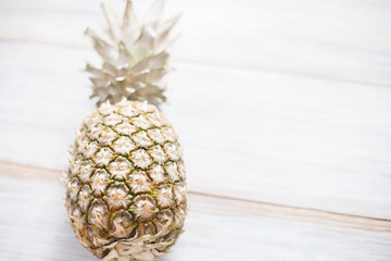 A whole ripe pineapple on an old wooden background.