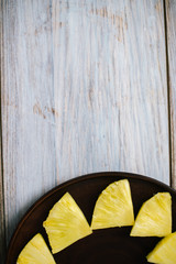 Pieces of pineapple on a wooden background chopped