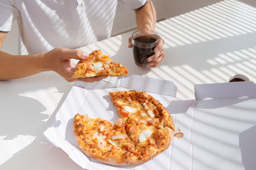close up man hand eating pizza while working in laptop computer