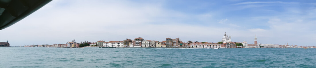 Fototapeta na wymiar Venedig mit Blick auf Kirche Santa Maria della Salute und Campanile mit Boote und blauen Wolken Himmel als Panorama