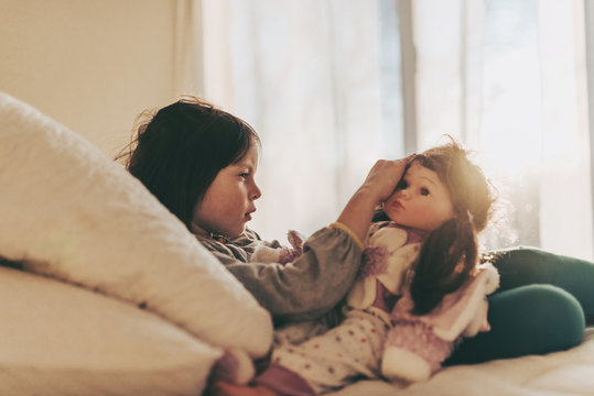 Girl sitting on her bed playing with a doll