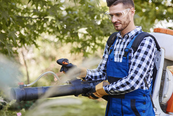 Gardener using leaf blower at garden