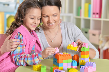 little girl and her mother playing with colorful plastic blocks