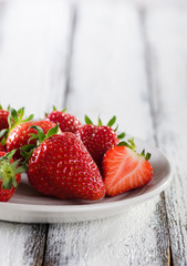 Fresh ripe red strawberries in white plate on white wooden rustic background