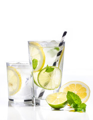 Glass of lemonade with lemon, lime and mint on white background