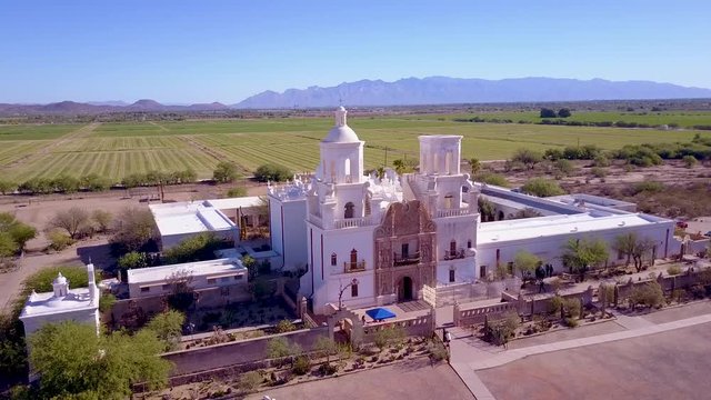 A beautiful aerial establishing shot of Mission San Xavier del Bac, a historic Spanish Catholic mission near Tucson, Arizona.