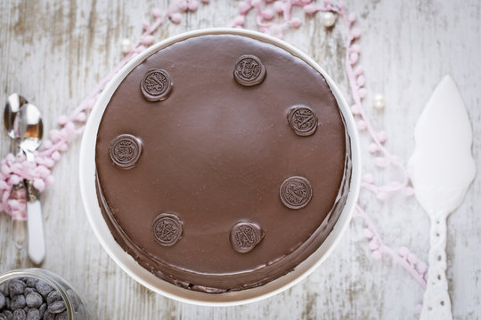 Overhead view of a chocolate cake (sachertorte) on a cakestand on a weathered table with a cake server and cutlery