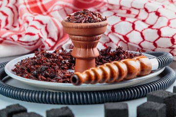 hookah with Apple flavor in a clay bowl, cooked for Smoking, stands on a tray