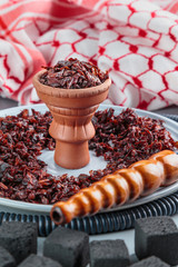 hookah with Apple flavor in a clay bowl, cooked for Smoking, stands on a tray